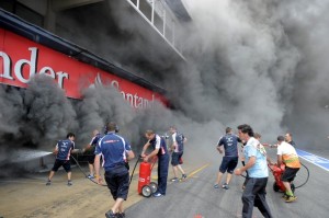 Racing team crews try to extinguish a fi